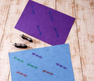 Hand carved arrow stamps with printed arrow patterns on purple and blue handmade paper.