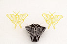 Hand-carved luna moth stamp printing simple symmetrical moth pattern on paper.