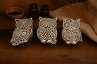Set of three hand carved wooden owl stamps with detailed folk art patterns displayed on a rustic wooden surface
