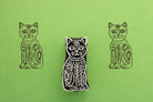 Hand carved wooden stamp featuring a floral folk art cat design printed in dark ink on green paper