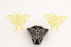 Hand-carved luna moth stamp printing simple symmetrical moth pattern on paper.