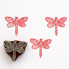 Hand carved wooden stamp featuring an ornate dragonfly with detailed patterned wings printed in red ink
