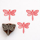 Hand carved wooden stamp featuring an ornate dragonfly with detailed patterned wings printed in red ink