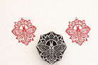 Hand-carved mandala moth stamp printing intricate symmetrical insect design on paper.