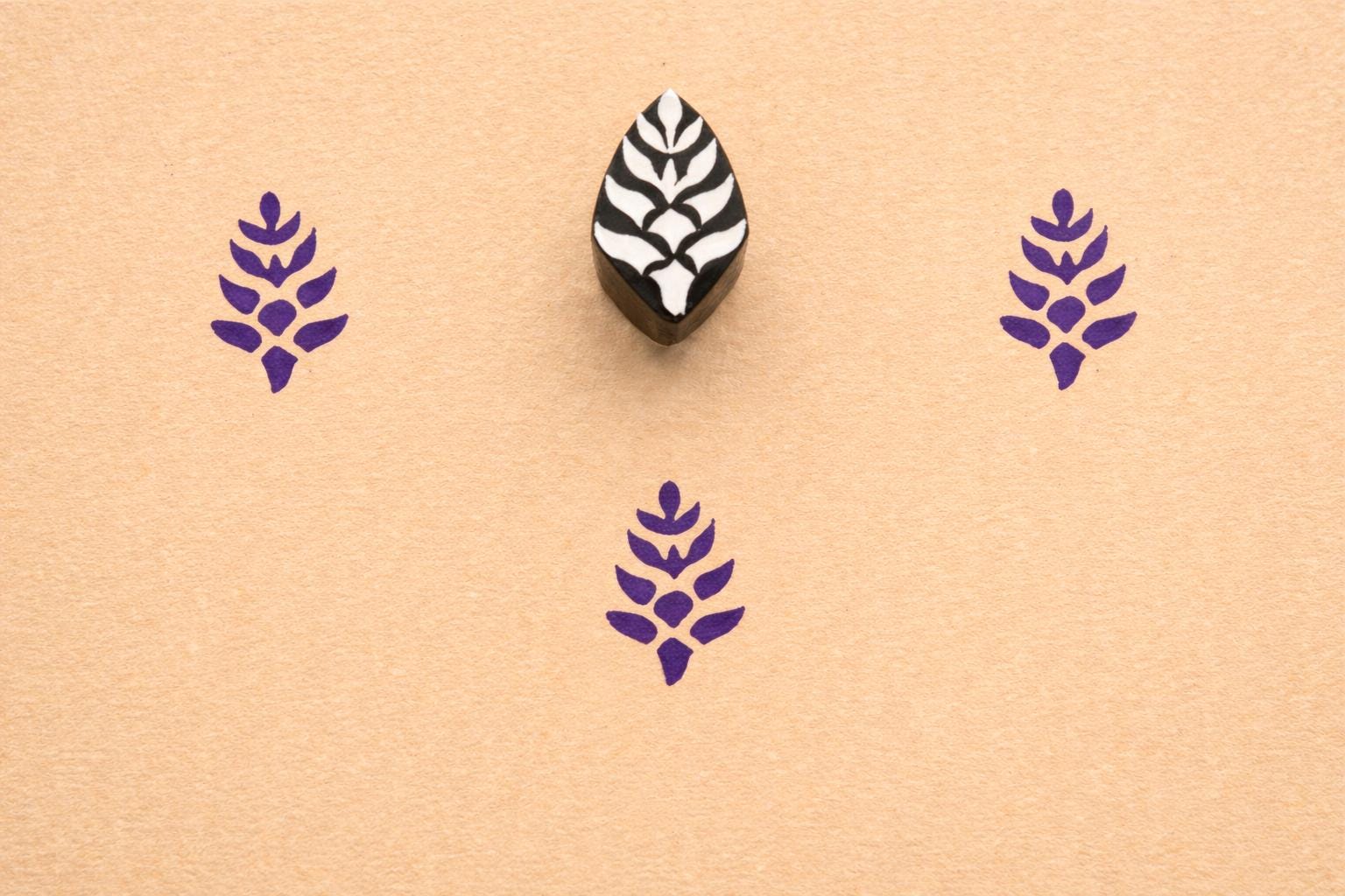 Hand carved small botanical leaf stamp printed in purple ink on textured paper