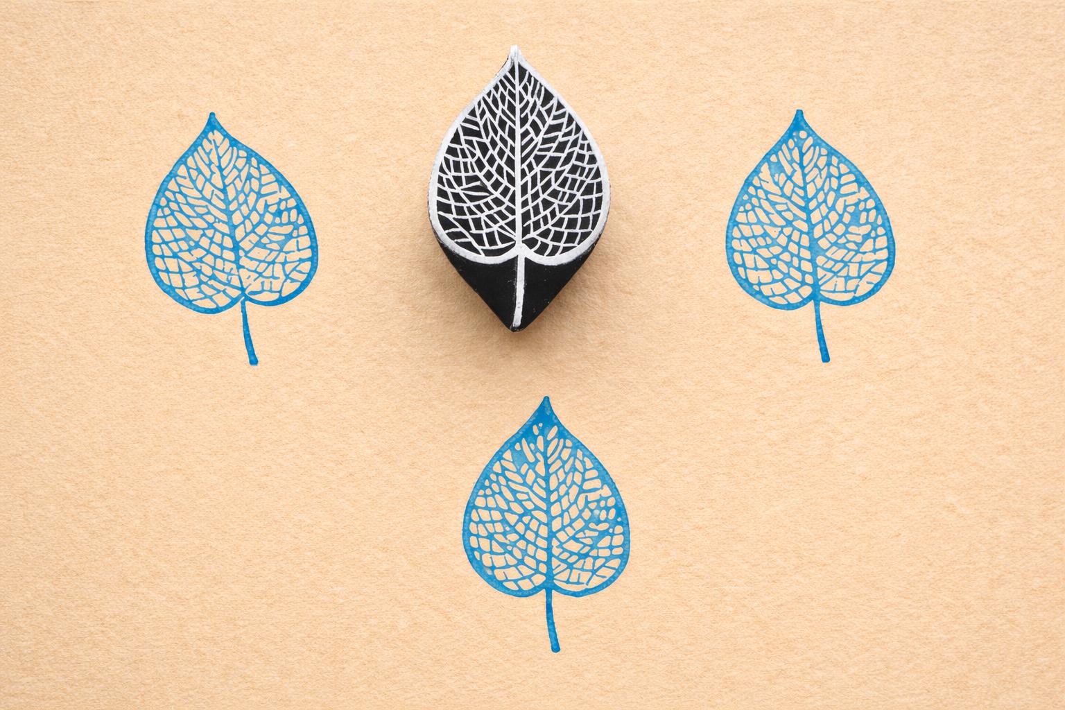 Veinleaf hand carved wooden stamp creating detailed blue botanical leaf prints on textured paper