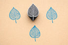 Veinleaf hand carved wooden stamp creating detailed blue botanical leaf prints on textured paper