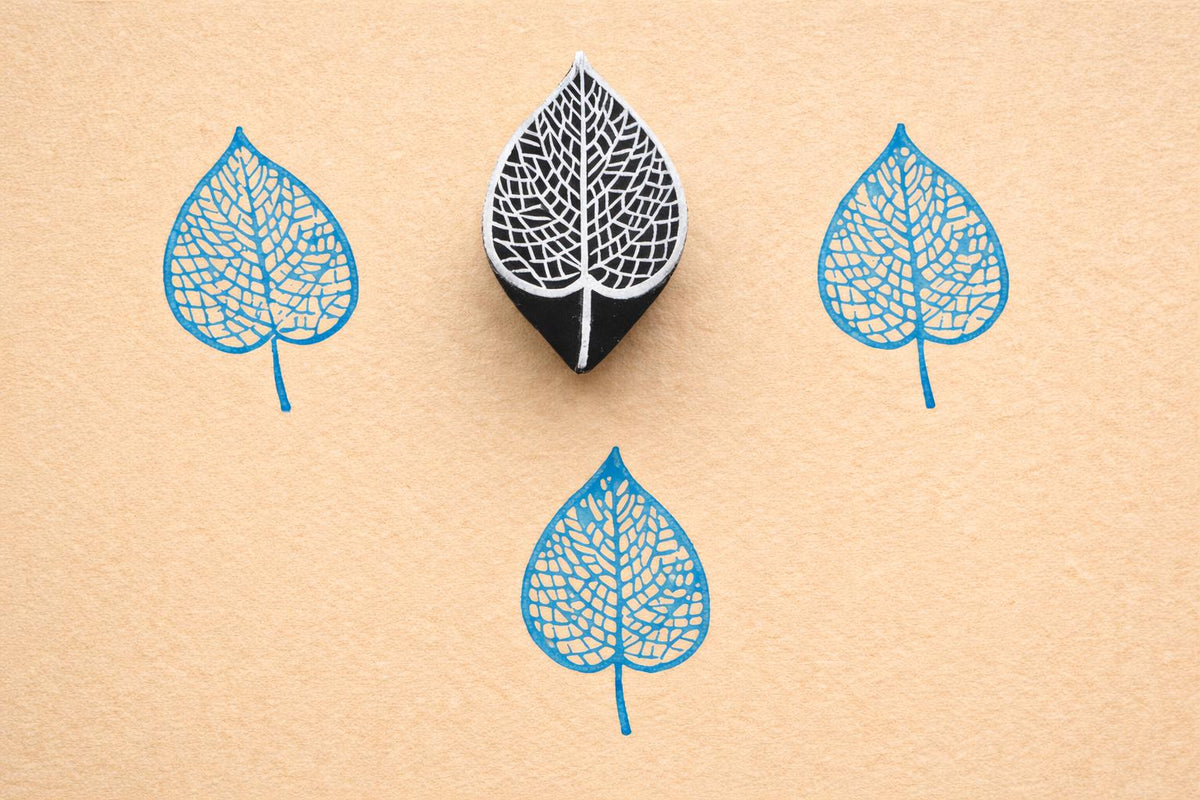 Veinleaf hand carved wooden stamp creating detailed blue botanical leaf prints on textured paper
