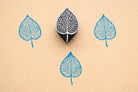 Veinleaf hand carved wooden stamp creating detailed blue botanical leaf prints on textured paper