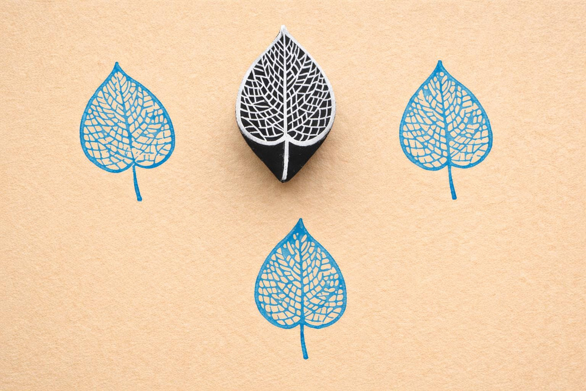 Veinleaf hand carved wooden stamp creating detailed blue botanical leaf prints on textured paper