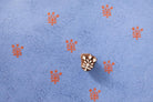 Fern branch wooden block printing stamp making orange prints on textured blue handmade paper.