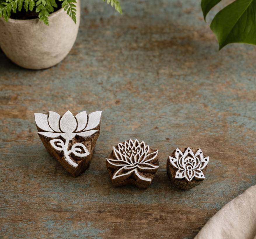 Set of three hand carved wooden lotus block stamps on rustic surface
