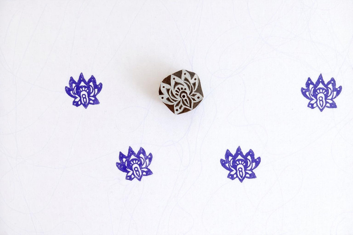 Purple small lotus flower block print pattern on white fabric using wooden stamp