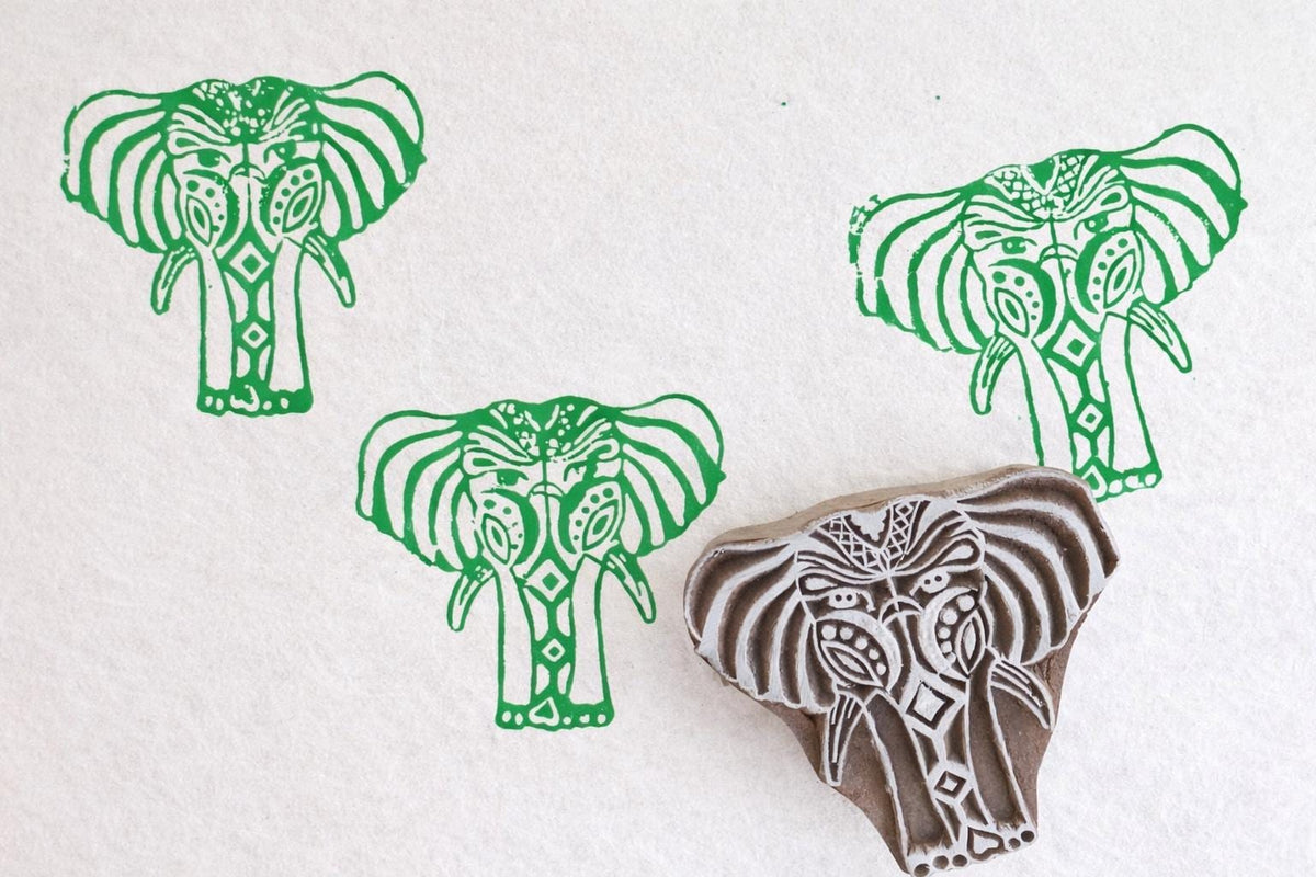 Hand carved elephant stamp creating green block print pattern on paper