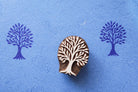 Hand carved wooden tree block printing stamp with detailed branches, shown with blue ink impressions on paper for textile and craft printing