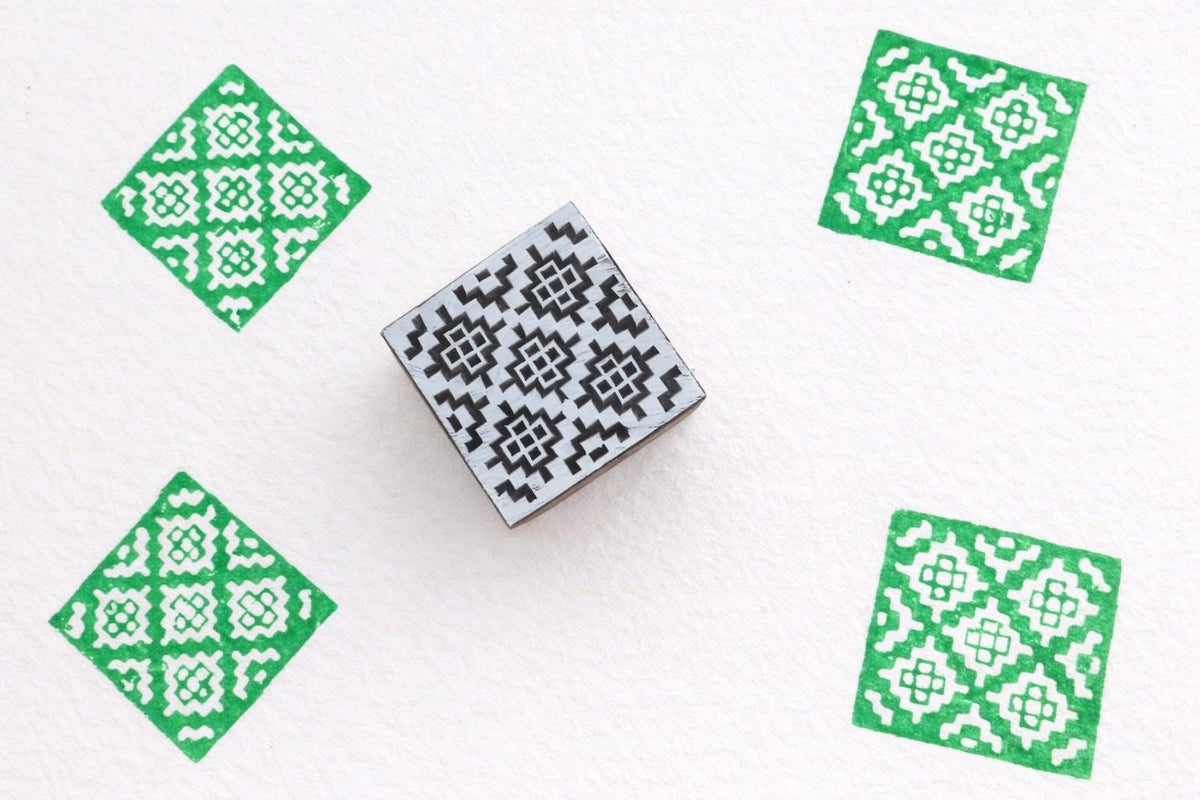 Hand carved wooden stamp printing green diamond geometric pattern on fabric