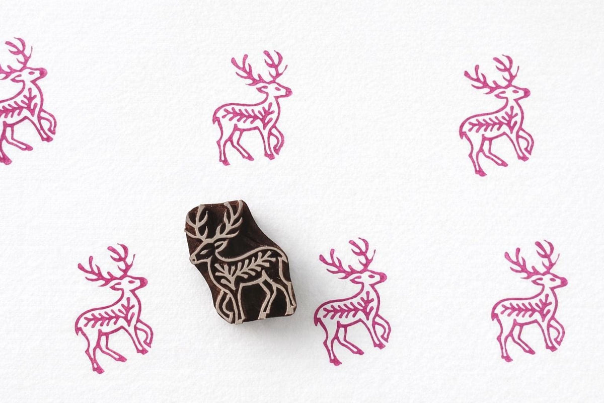 Deer block print pattern in pink ink on paper with wooden stamp