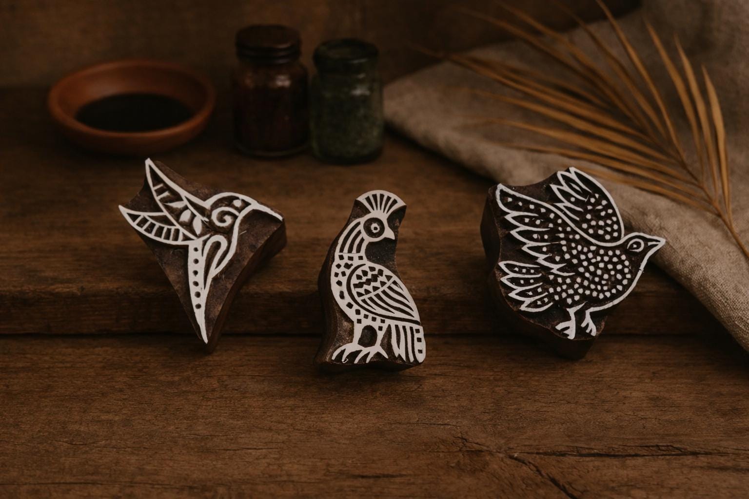 Set of three hand-carved wooden block stamps with bird designs on rustic background