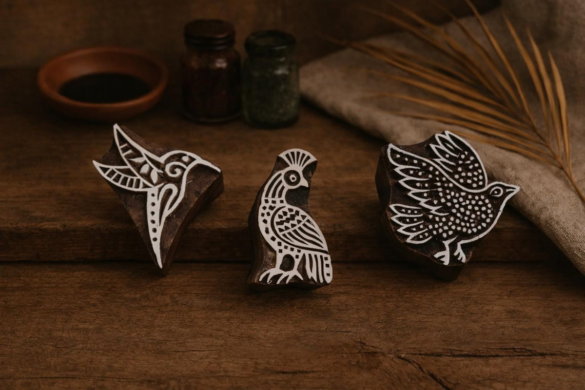 Set of three hand-carved wooden block stamps with bird designs on rustic background