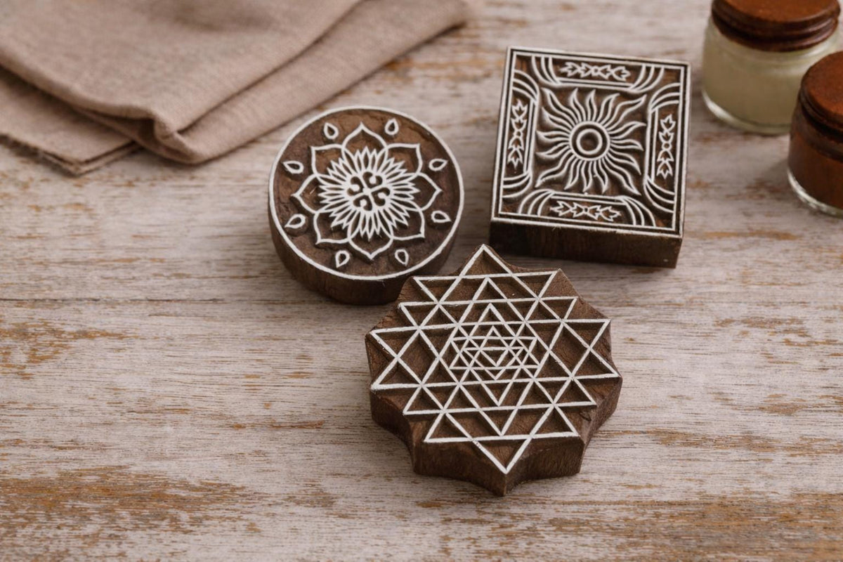 Set of three handmade wooden block print stamps including floral mandala, sun tile, and sacred geometry star