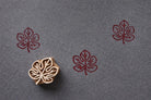 Hand-carved wooden maple leaf block stamp with red leaf prints on fabric in a minimalist nature style