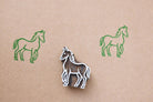 Hand-carved wooden horse block stamp with green horse prints on paper in a minimalist folk art style
