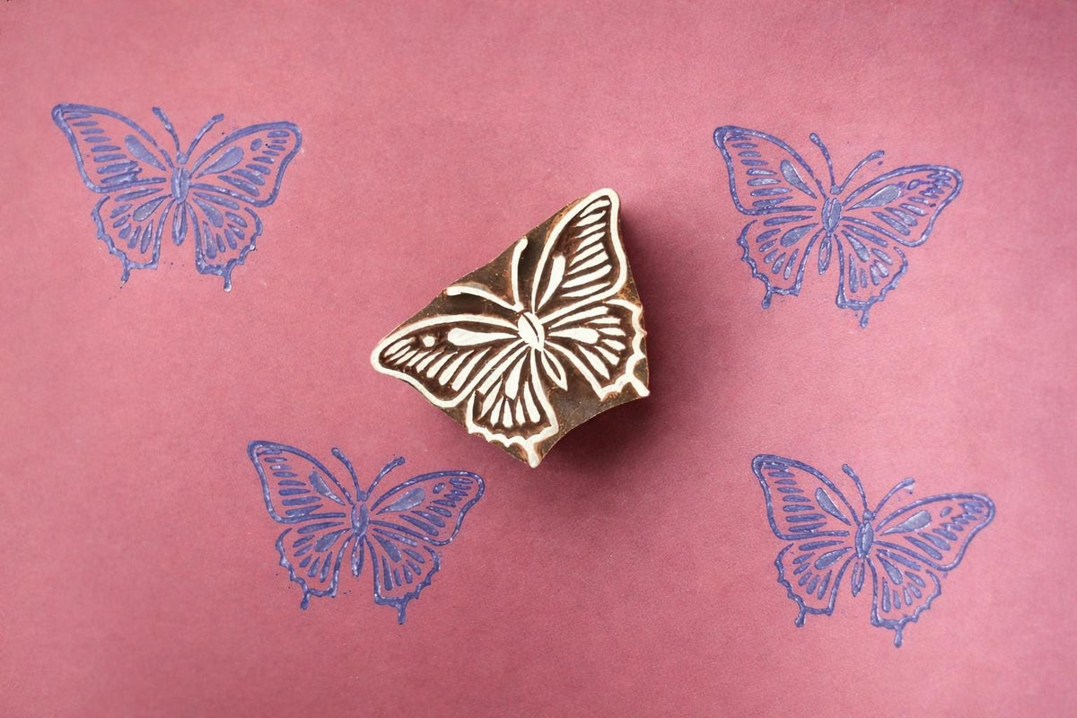Hand-carved detailed butterfly stamp with blue prints on paper