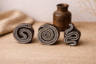 Set of three hand-carved wooden snake block stamps with detailed serpent patterns on rustic background