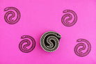 Coiled snake wood block stamp with black serpent prints on bright pink background