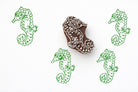 Hand carved seahorse wood block stamp with repeating printed pattern on paper