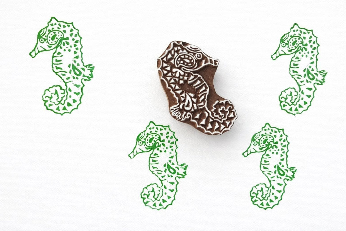 Hand carved seahorse wood block stamp with repeating printed pattern on paper