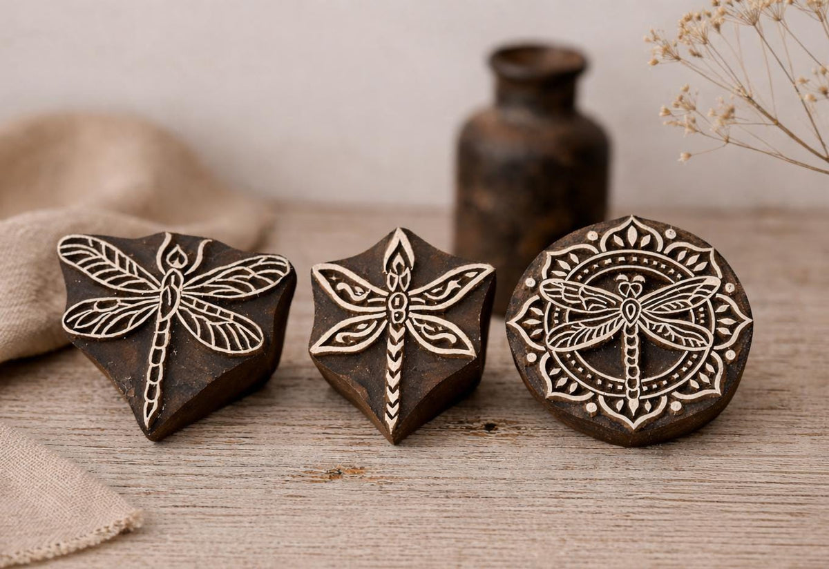 Set of three hand-carved wooden dragonfly block stamps with detailed wing patterns on rustic background