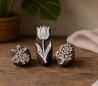 Hand carved floral wood block stamp set with tulip, daisy and wildflower designs on wooden surface