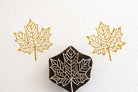 Crownleaf wooden stamp producing intricate gold maple leaf prints on white textured background