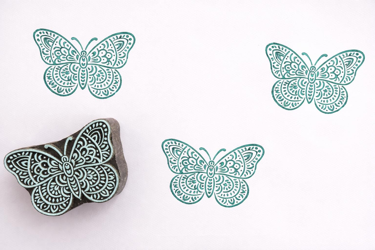 floral butterfly stamp with teal prints on white background