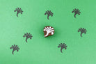 Small hand carved wooden block stamp with abstract botanical sprig design printed in repeating pattern on green background
