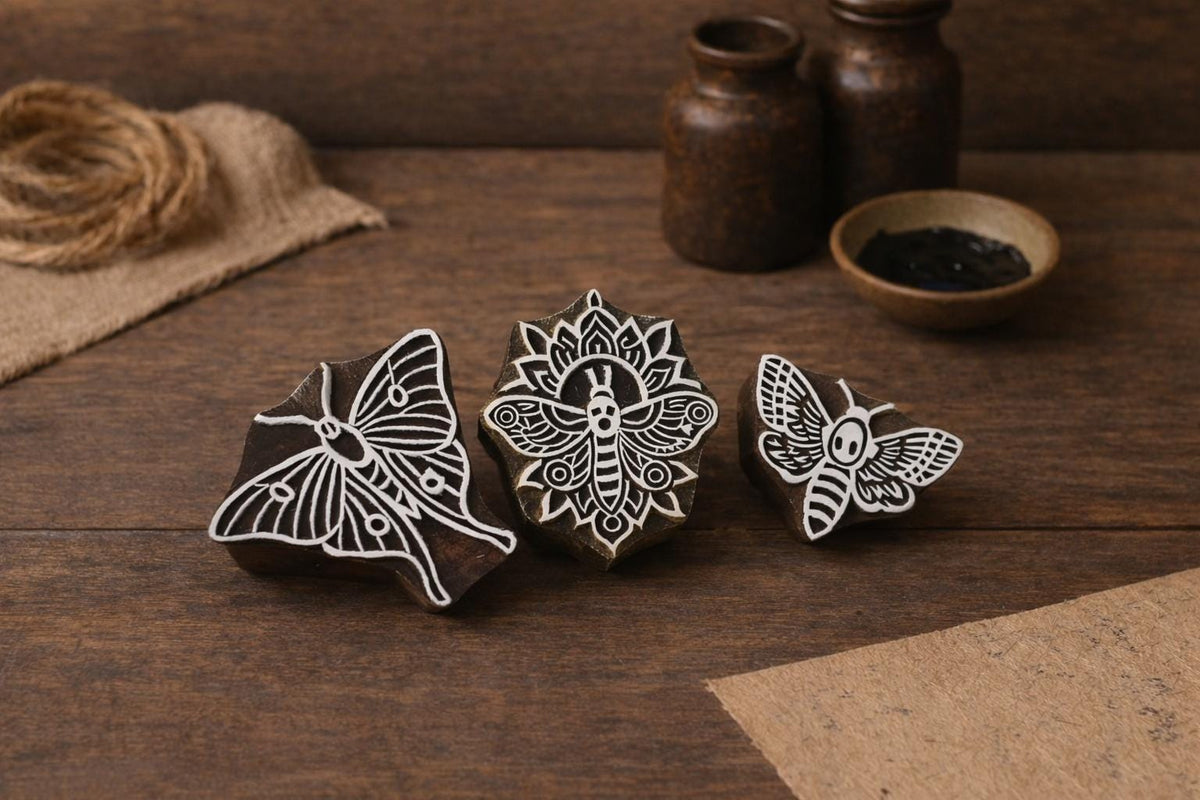 Set of three hand-carved wooden moth stamps with luna and mandala designs on a rustic wooden surface.