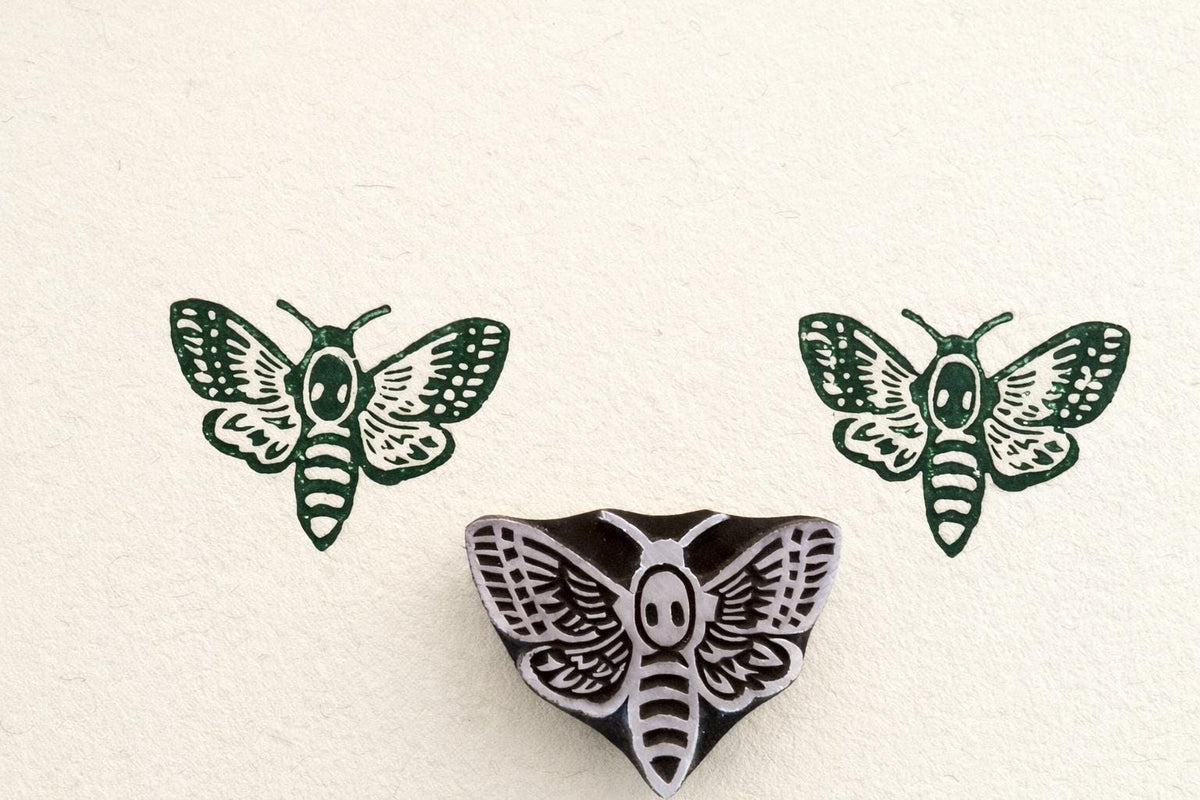 Hand-carved detailed moth stamp printing decorative wing pattern on paper.