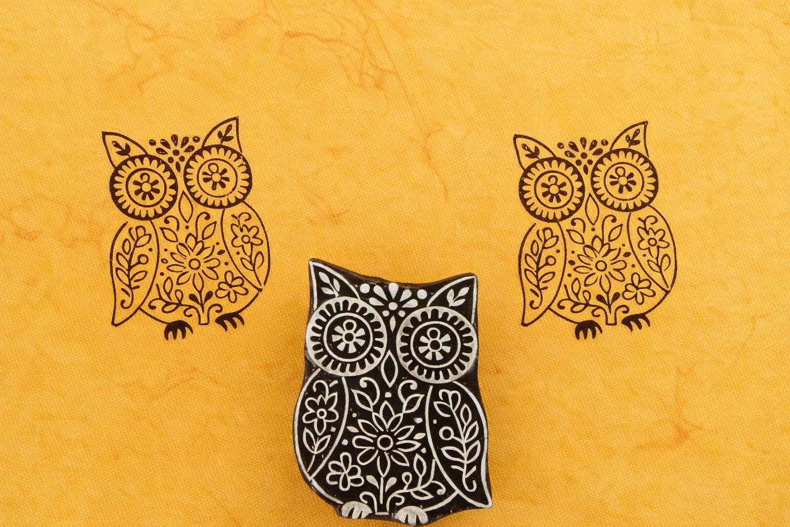 Hand carved wooden owl stamp featuring floral folk art patterns printed in dark ink on yellow paper