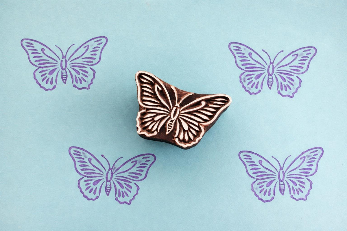 Folk art butterfly wood stamp with blue butterfly prints on blue background