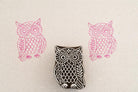 Hand carved wooden owl stamp with feather pattern design printed in pink ink on textured paper