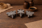 Set of three hand carved wooden block stamps featuring different dragonfly designs on a rustic wooden surface
