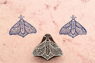 Glyph Moth hand carved stamp with geometric wing details printed in blue ink on paper