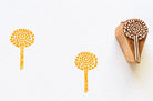 Hand carved wooden stamp with circular sunburst flower design and stem