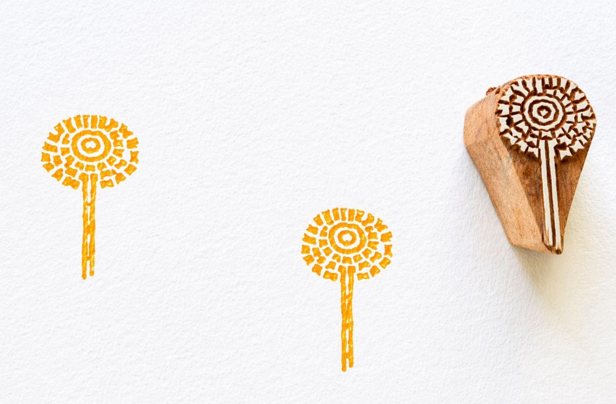 Hand carved wooden stamp with circular sunburst flower design and stem