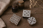 Set of three handmade wooden block print stamps with geometric patterns on rustic surface