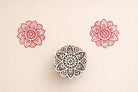 Hand carved wooden stamp printing red floral mandala pattern on fabric