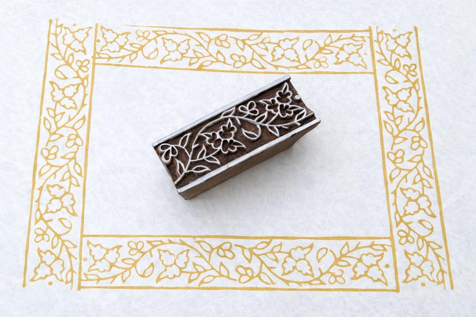 Hand carved wooden stamp printing floral vine border pattern with flowers and leaves