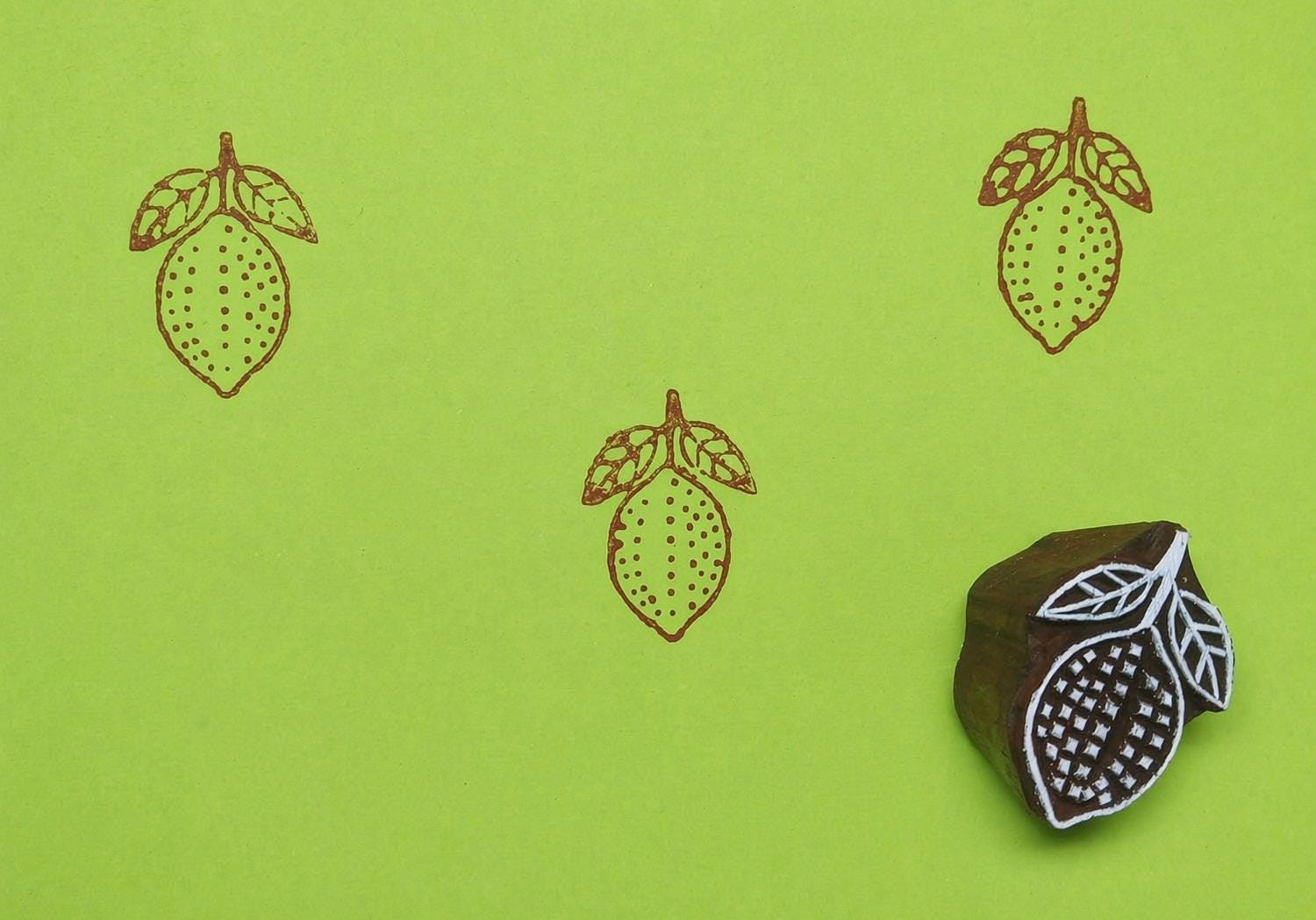 Lemon wooden printing block creating repeating fruit pattern on green background