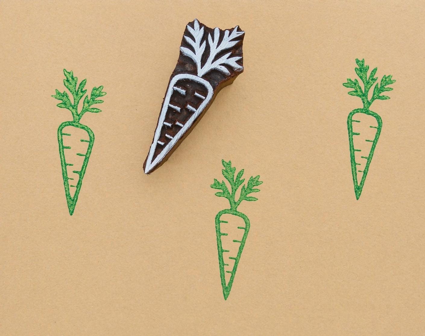 Hand carved carrot stamp with green ink prints on kraft paper